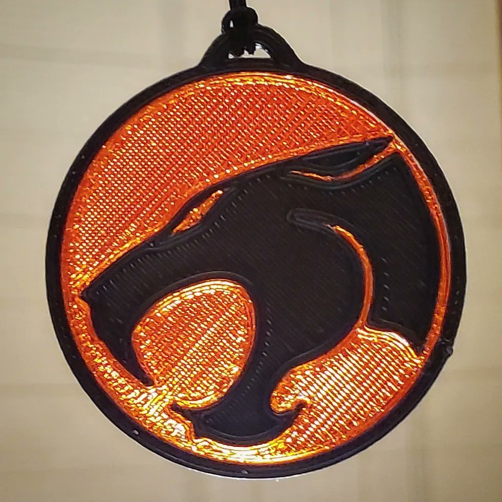 artmarchdraws's tweet photo. Experimenting with my last remnant of a red translucent filament from @polymaker_3d , finding the detail I can get from a 0.4mm nozzle. I modeled the #ThunderCats logo for this test, thought it'd make a neat ornament for my desk lamp. #idexprinter #3Dprinting #80scartoons https://t.co/Lzp96UIU6w