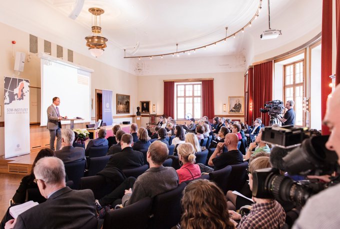 Foto från SOM-seminariet 2015. En man presenterar och publiken lyssnar. En kamera i förgrunden.
