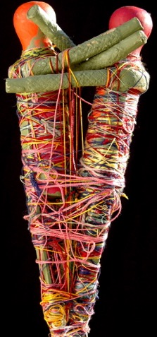 Une œuvre de Judith Scott, deux figure humanoïde se tenant dans les bras, constitué d'objets enroulés dans des fils de laine colorés.