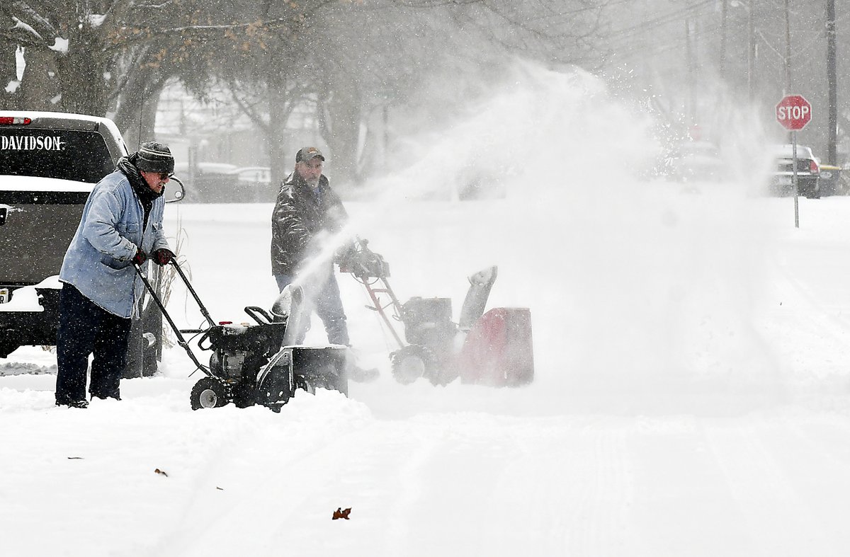 Tim Dunn and Tim Holt work together with their snowblowers to help dig out their neighbors in the 500 block of Coventry Drive Thursday.