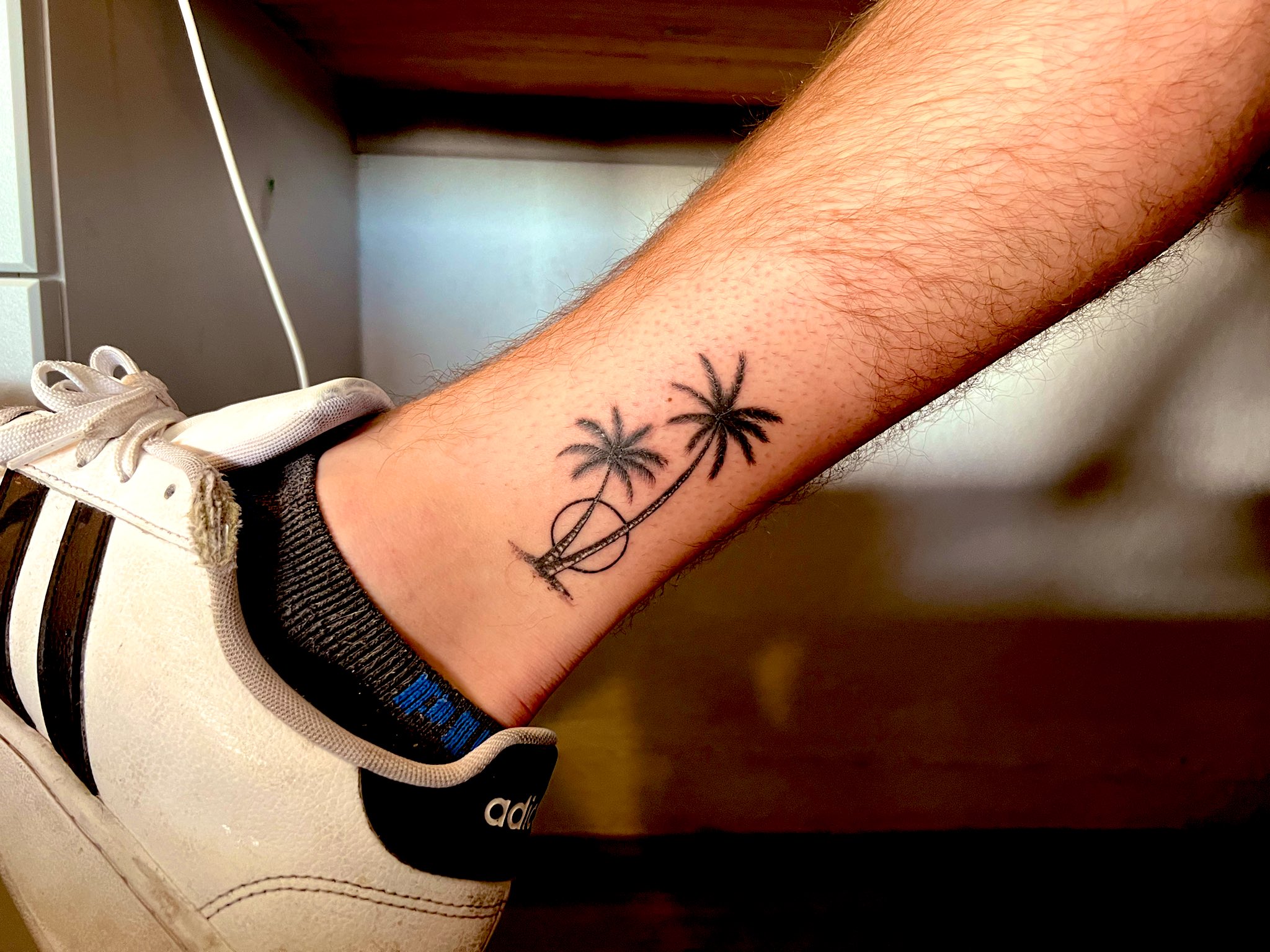 Date and pine tree tattoo located on the wrist.