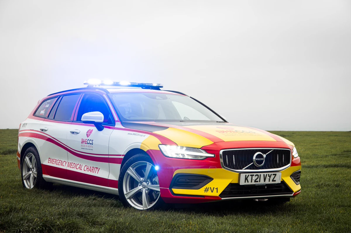 A Volvo v60 in white, red and yellow with flashing blue lights