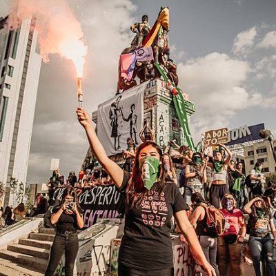Women at a march against sexist violence in Chile. Many of them wear green bandanas or scarves. 