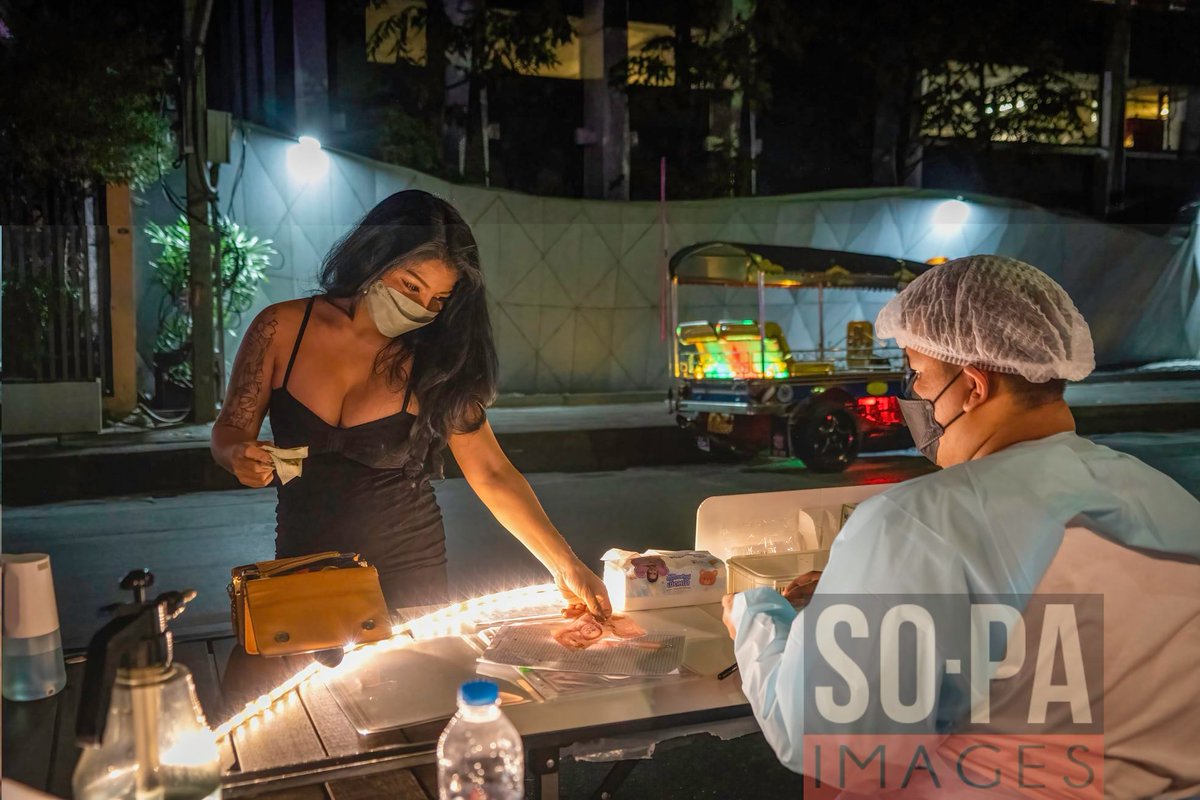 sopaimages's tweet photo. A woman pays for an ATK swab test at the entrance to #SoiCowboy in #Bangkok, #Thailand on January 27, 2022. Mandatory ATK (#AntigenTestKit) swab tests (Cost: 120 Thai Baht, $3.60) are administered from a temporary entrance station at Soi Cowboy. Photo by Matt Hunt / SOPA Images https://t.co/Rtfm4IOpDY