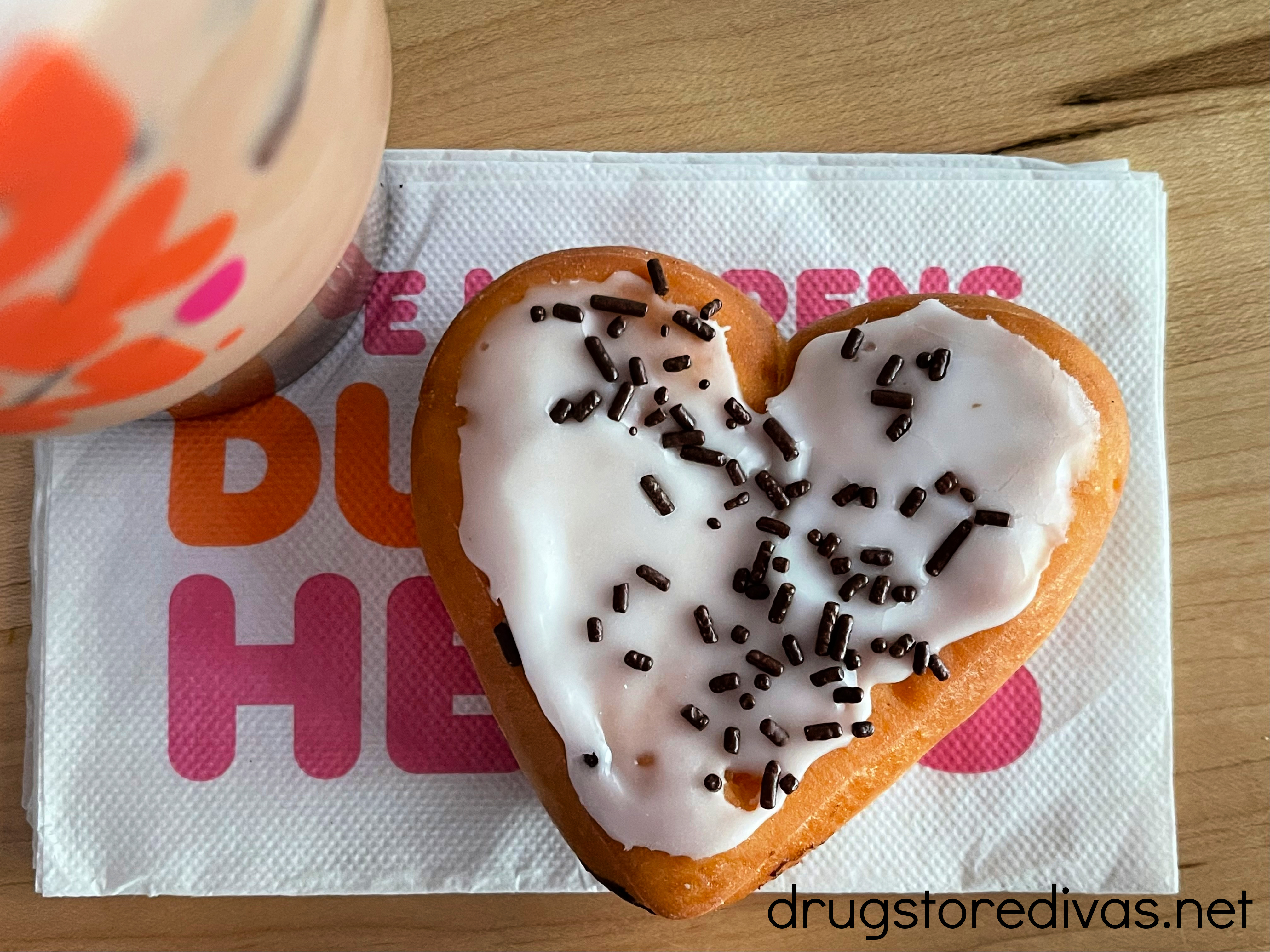 Heart shaped donut and coffee on a napkin.