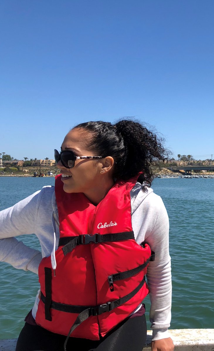 A woman scientist stands on a small research boat.