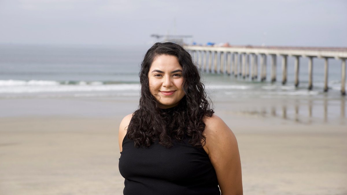 Portrait of a woman standing near the beach and a research pier.