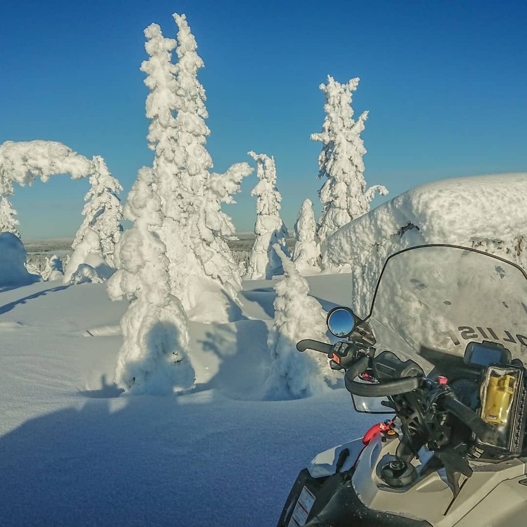 Tykkylumipuista heijastuu poliisin moottorikelkka