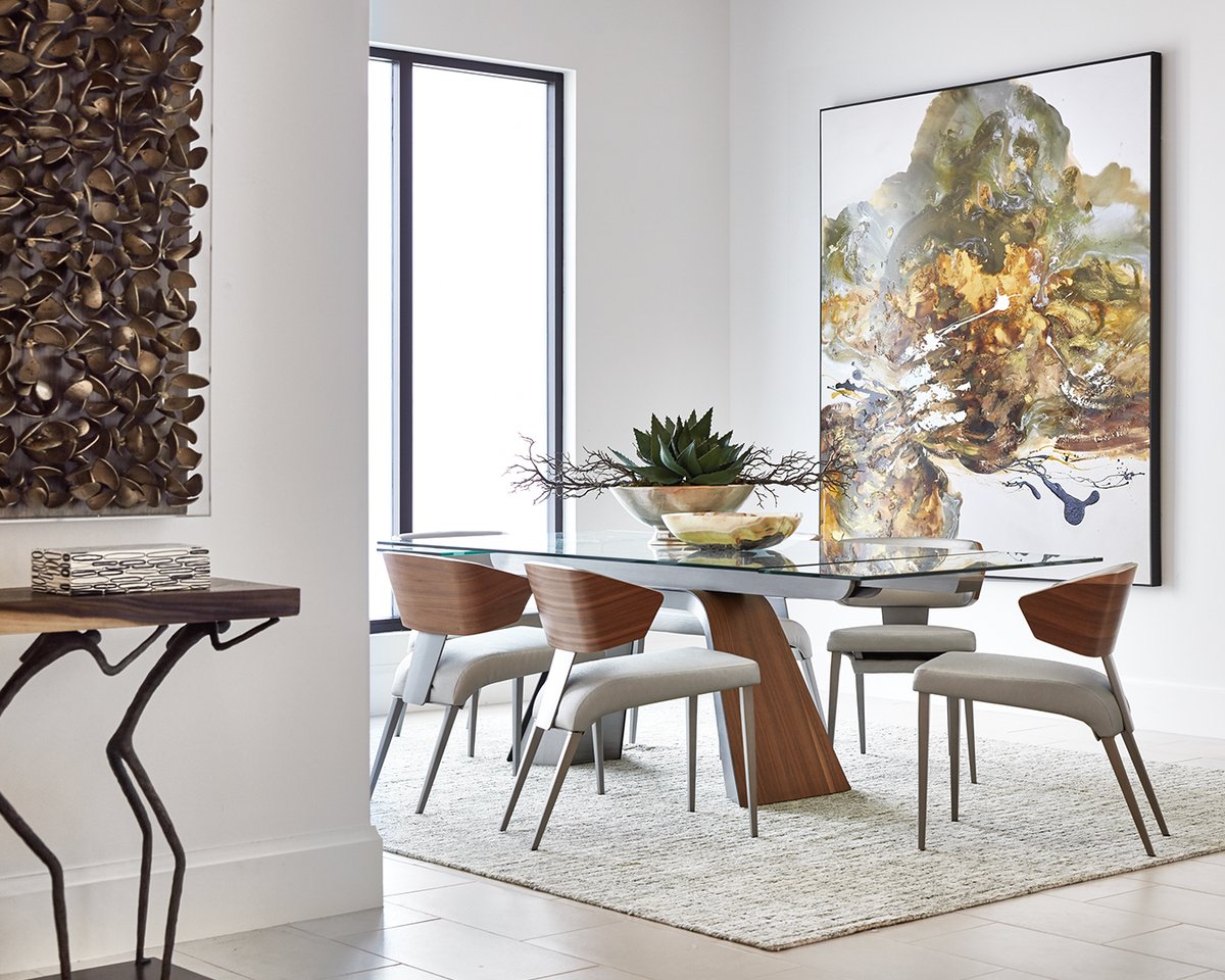 The boldly sculpted Harlan Dining Table features a dramatic splayed base with angled brushed stainless steel panels wrapped in a continuous plane of walnut veneer. Shown paired with the matching Cosette Side Chair. ____________________________ #robbstucky #interiordesign