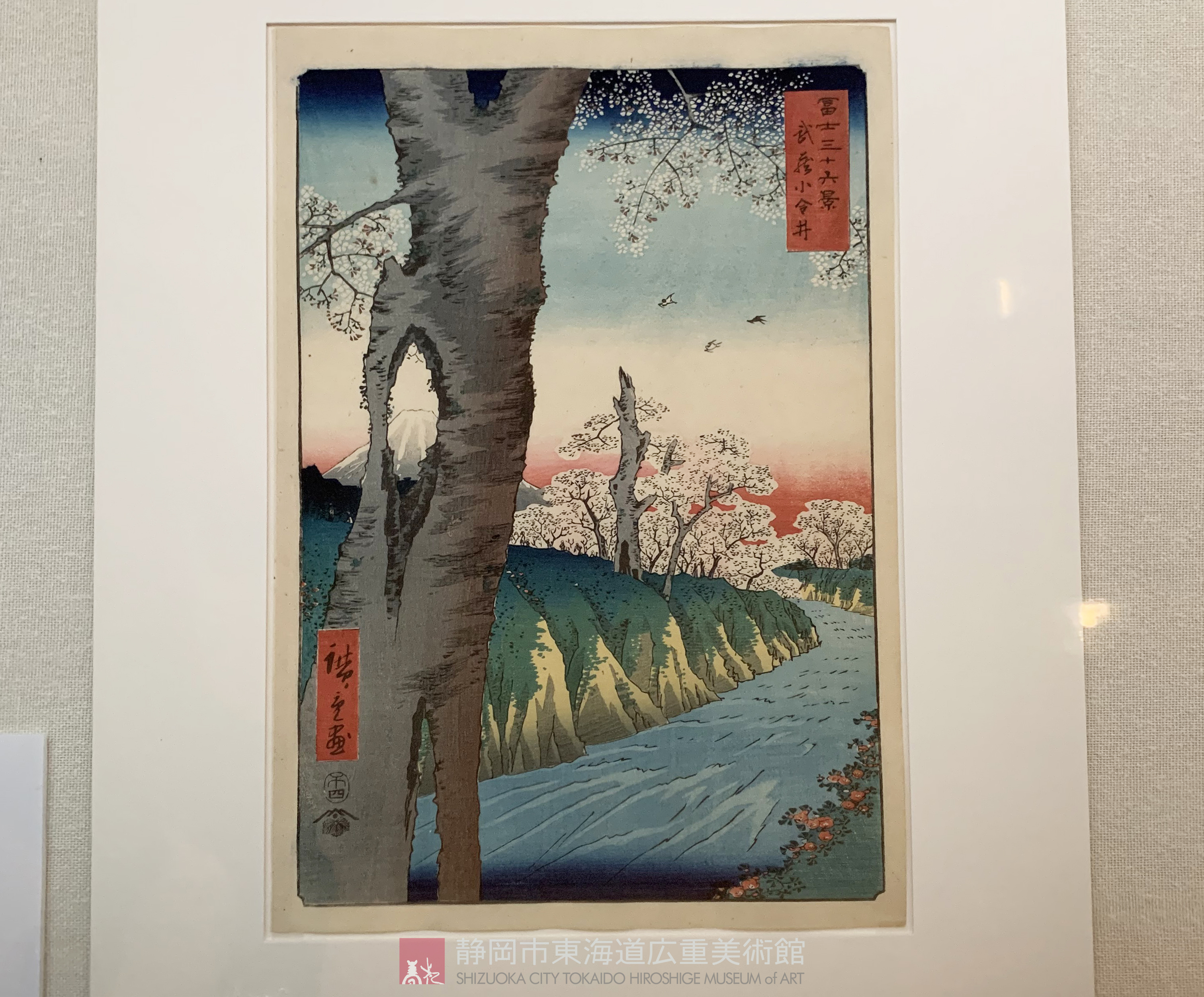 東海道広重美術館 武蔵小金井 本図は 桜の樹を手前に大きく配し 木の洞から富士山の姿をのぞき見る という奇抜な構図で描かれています ゆるやかにカーブを描く玉川上水の流れが手前から奥へと目線を誘い 遠近感を強調している作品です T