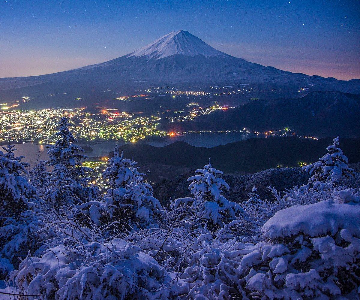 雪後の夜明け 空が明るくなり始め、降雪の木々、山麓の街灯りが輝く 新道峠で以前撮影。