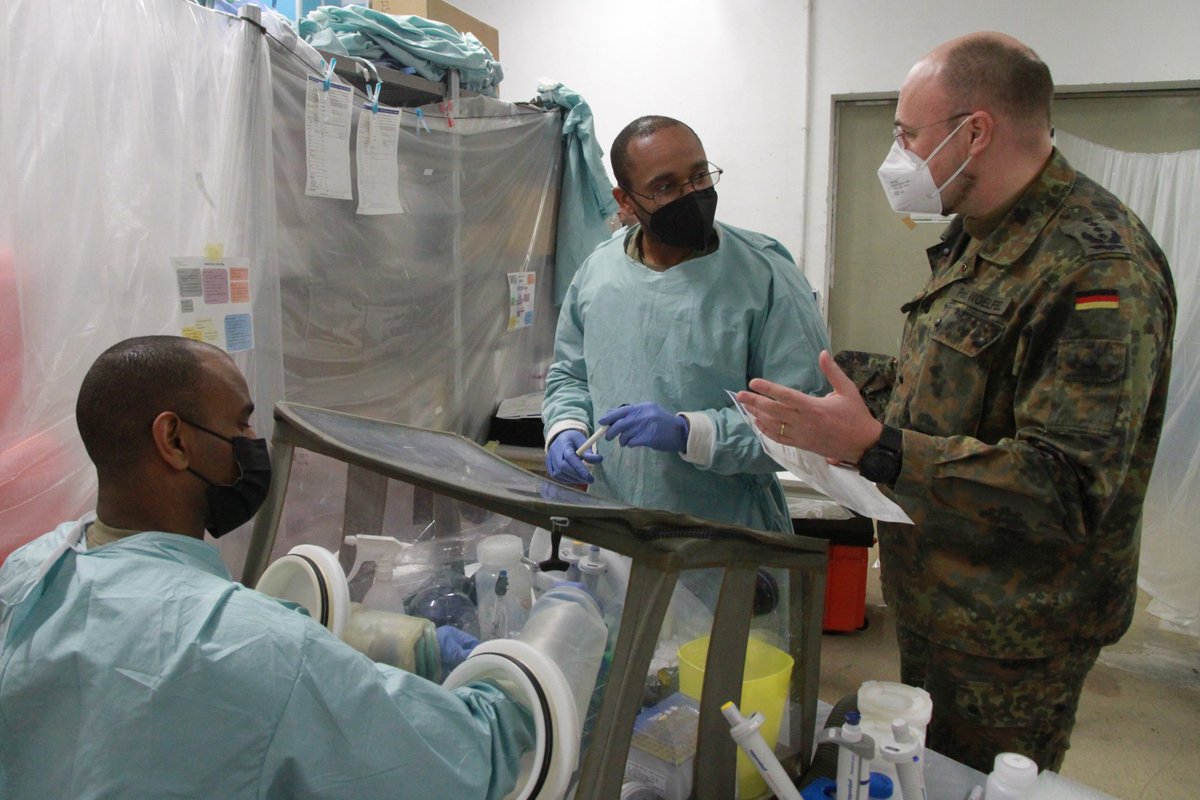 Ein Mann in Uniform und zwei in Kitteln unterhalten sich