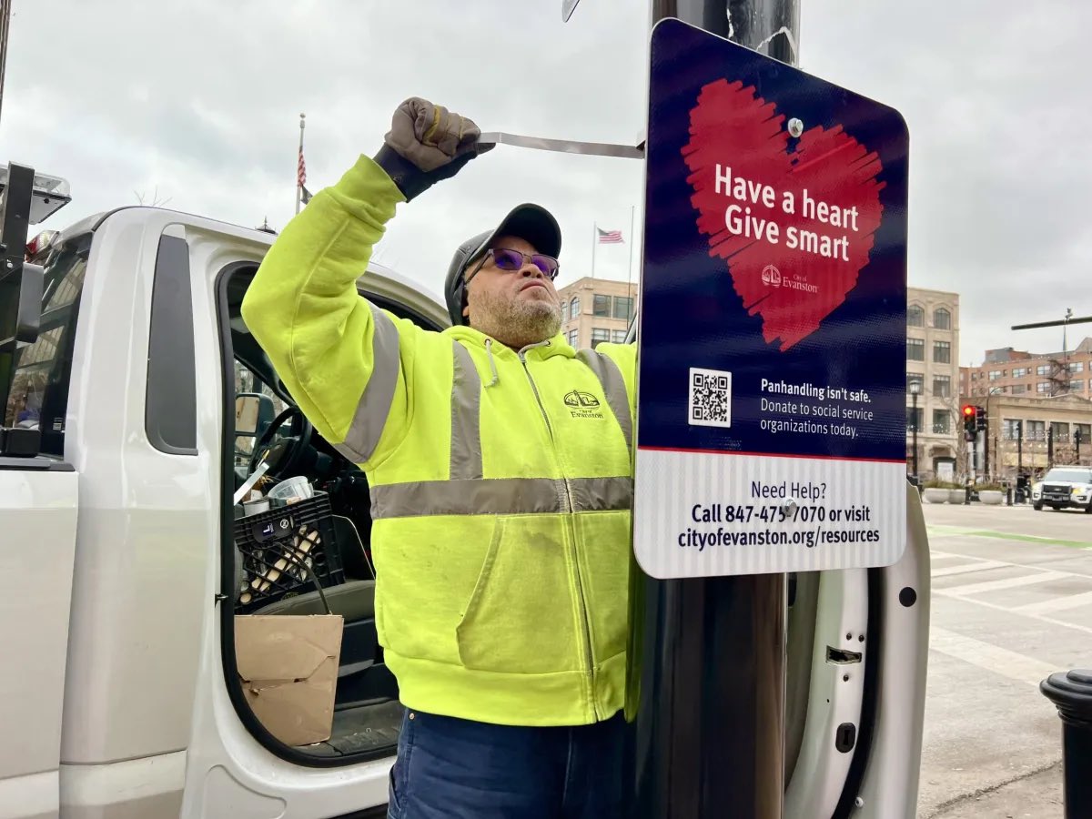 At This Time, Thursday at 9:21 a.m. Gerald Franklin installs the first of 30 signs that discourage giving to people on the street. “This is not about general panhandling, but about aggressive panhandling, which is criminal,” said Kelley Gandurski, interim city manager.