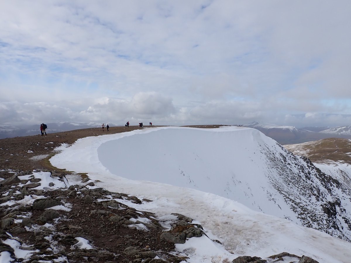LakesWeather's tweet photo. A good illustration of the current contrast in ground conditions. Bare ground on the summit plateau but lots of snow on high east facing slopes. Potentially unstable #windslab and small #cornices lurking high up on these steep scarp slopes. Wes https://t.co/WqrG8WINsX