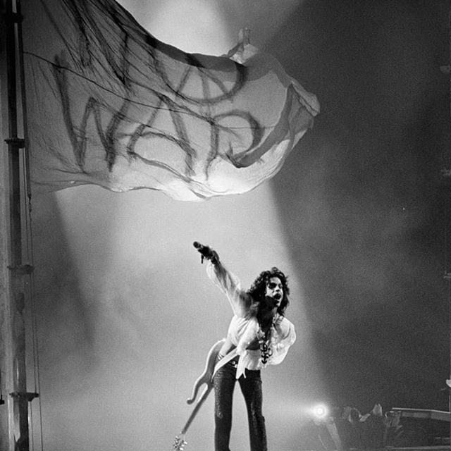 taja_sevelle's tweet image. #Prince, relevant as always and still making waves on the internet. This is from the 1988 #lovesexy tour. The flag says "No War," and has a peace sign for the O. (Photographer unknown, likely a screen capture from a video.) #NoWar #peace