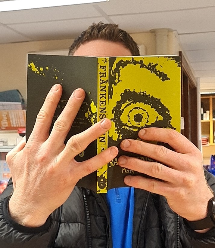 “The Masked Reader!” Which staff member do you think is hiding behind the book cover today? #worldbookday #maskedreader #day3