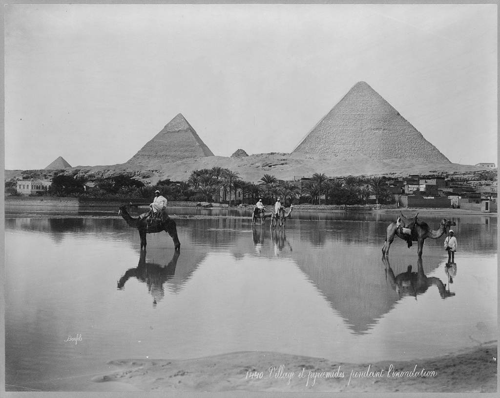 PhotosOfOld's tweet photo. Camels and riders stand on a flooded plain near the Pyramids in #Egypt ca. 1890s. #Africa #history #1800s #historicalphotos https://t.co/BSFVUbElI0