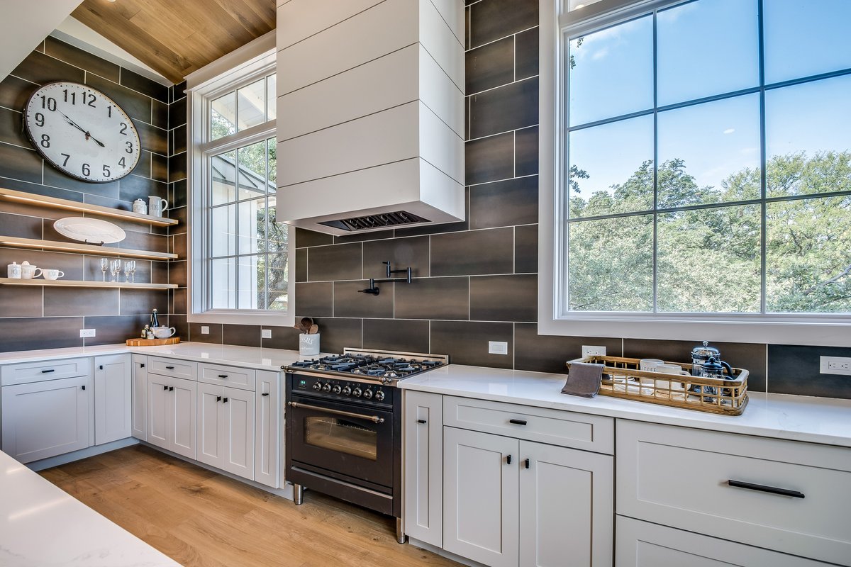 A tasteful take on a contemporary look hits some high notes - design wise. A focal stacked chimney hood works with a classy large format subway style charcoal brown tile. White quartz perimeter surfaces paired with a contrasting island and a quartz island with subtle veining.