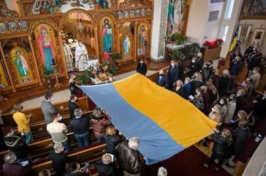 A large #Ukrainian flag is unfurled at the St. Michael the Archangel Ukrainian Catholic Church during a special prayer service in #Baltimore. Photo by Jerry Jackson <a href="/baltimoresun/">The Baltimore Sun</a>