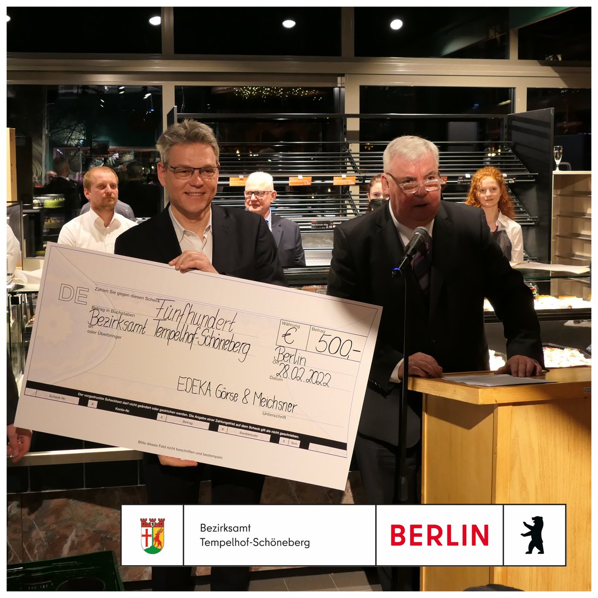 Ein Mann hat ein Check in der Hand in Höhe von 500€.