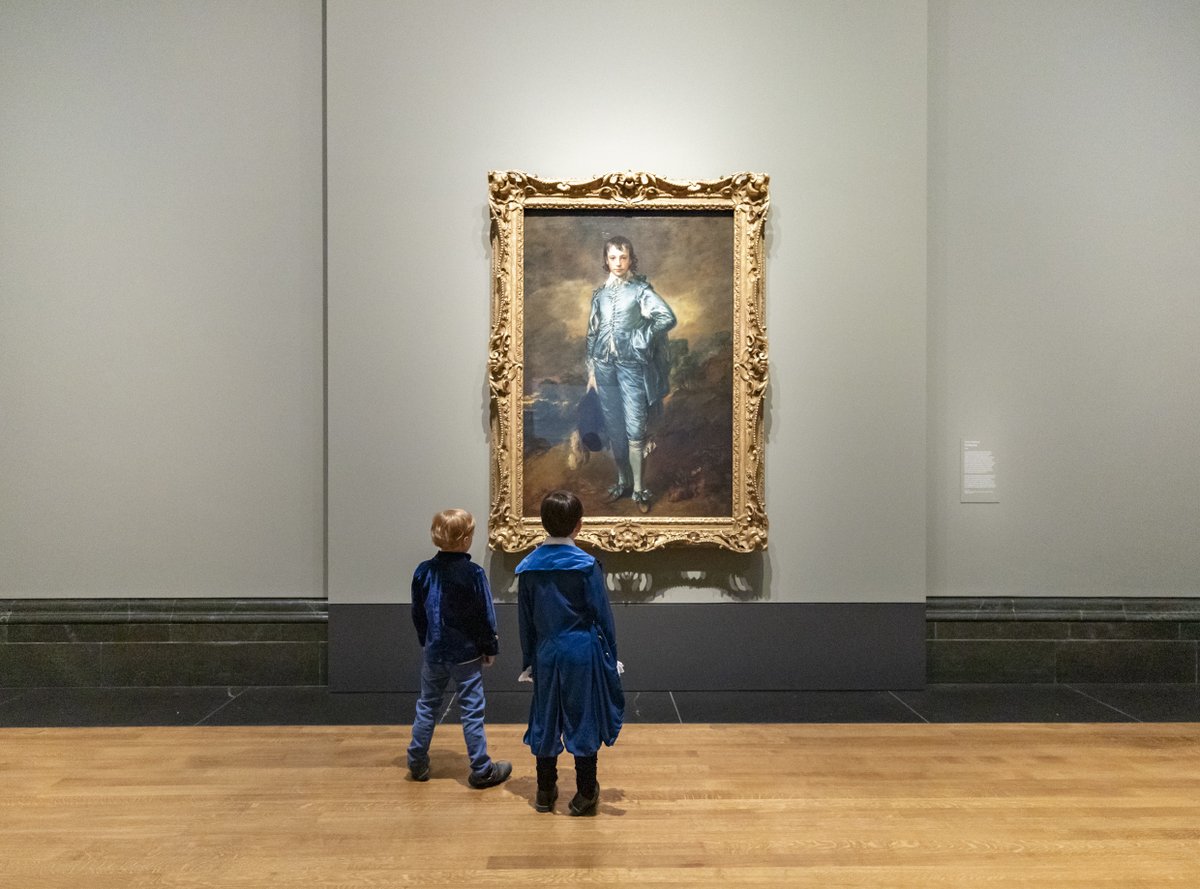 Two boys, dressed in blue, stand in front of Gainsborough's 'Blue Boy'.