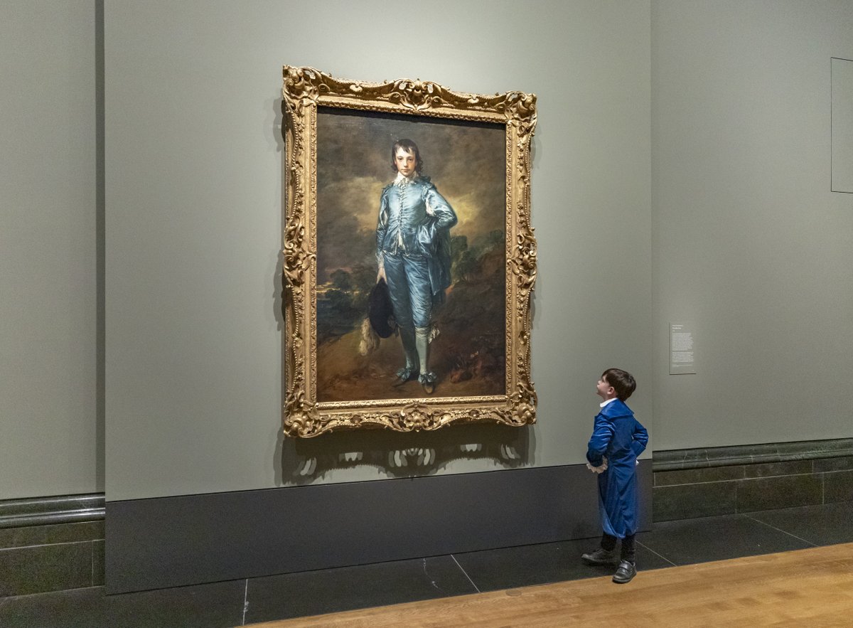 A boy dressed in blue looks up at Gainsborough's 'Blue Boy' painting.
