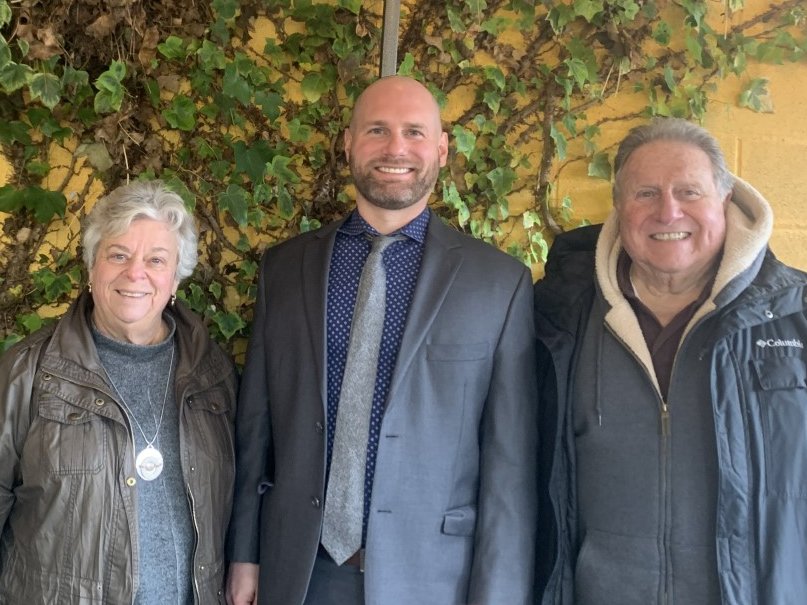 Mr. Dozler stands with representatives of civil society in front of a green wall. 