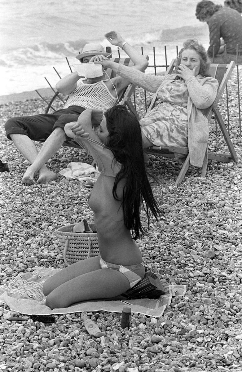 _Henk_Heijmans's tweet photo. Wife shields her husband’s eyes from a young woman taking her top off on the beach, France, 1974 - photographer unknown https://t.co/Q5KdTGGgYx