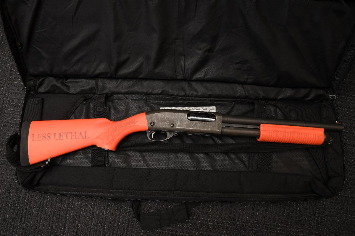 Black and orange less-lethal shot gun.