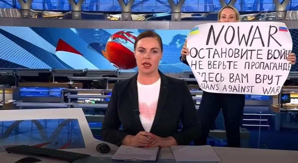 Ihr Name ist Marina Ovsyannikova, sie ist Produzentin des Senders, ihre Eltern sind Russin und Ukrainer, sie selbst ist Mutter von 2 Kindern und sie wurde nach dieser Aktion verhaftet. Ihr drohen 15 Jahre Haft.  Wir sollten sie nicht vergessen.