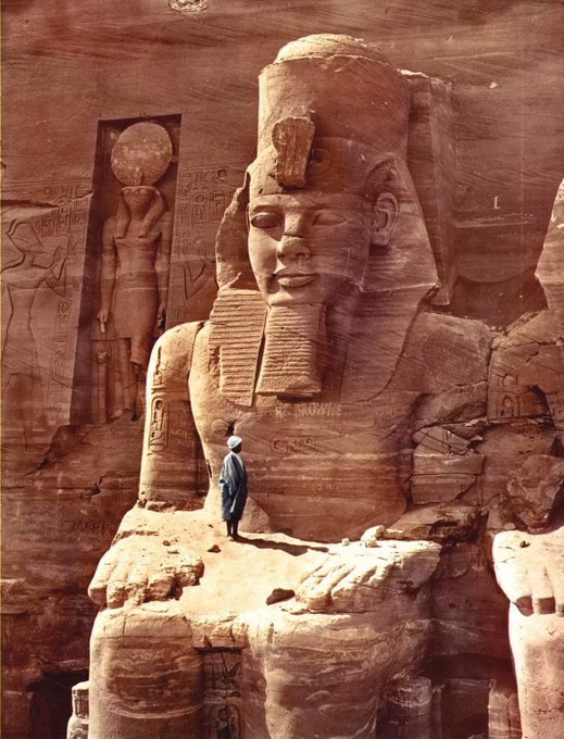 Colourised photo of a man standing on a colossal figure of Ramesses II at the temple of Abu Simbel, Egypt, 1865. Original photo by Francis Frith. More info here: rct.uk/collection/270…