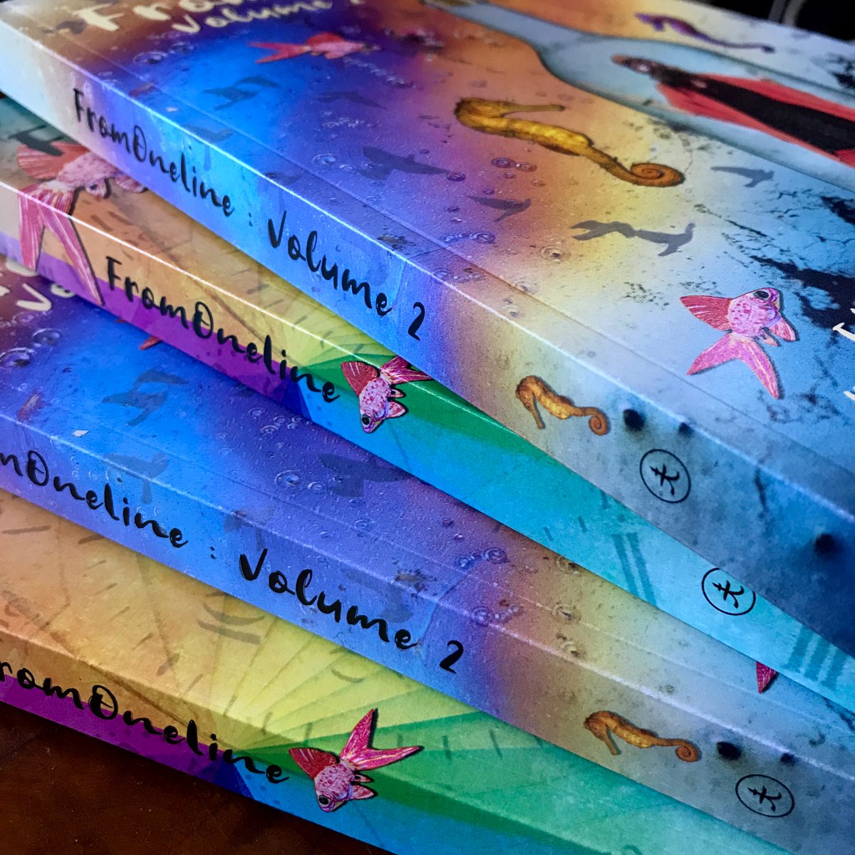 A photo of the spines of FromOneLine Volume 1 and Volume 2...  rainbow colours! 