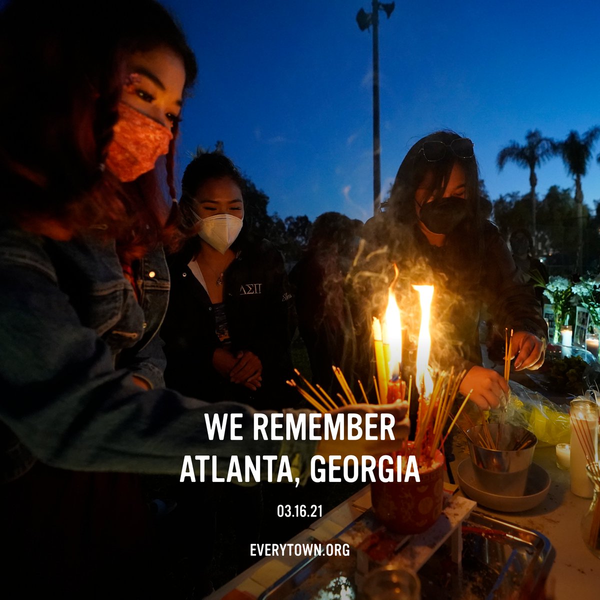 We remember Atlanta, Georgia. Three masked Asian American women stand in front of a memorial with lit incense and candles.