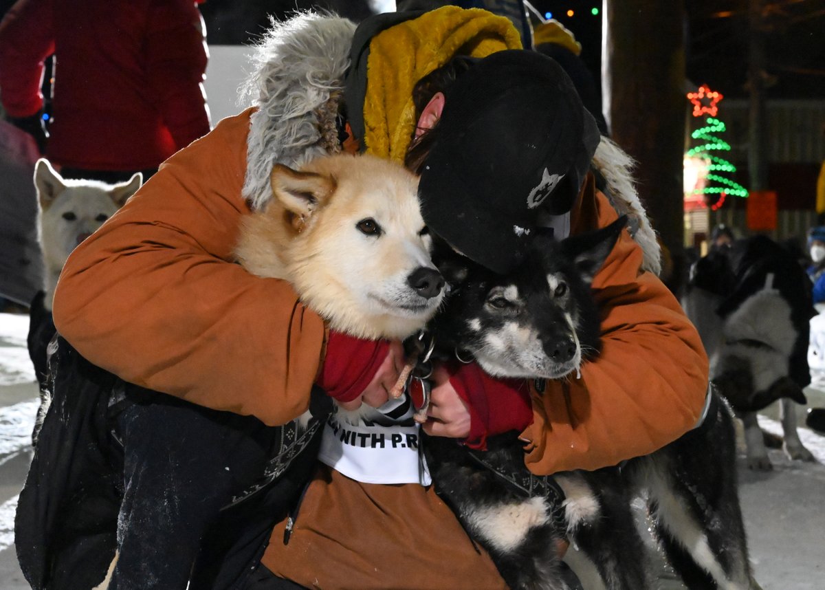 ADNIditarod's tweet photo. 2022 Iditarod winner Brent Sass hugs his lead dogs Slater, left, and Morello after arriving at the finish line in Nome.  (📷: Anne Raup/ADN) https://t.co/H5UsLlBW91