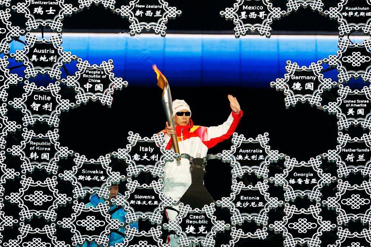 Torchbearer Li Duan holds the torch and waves to the crowd