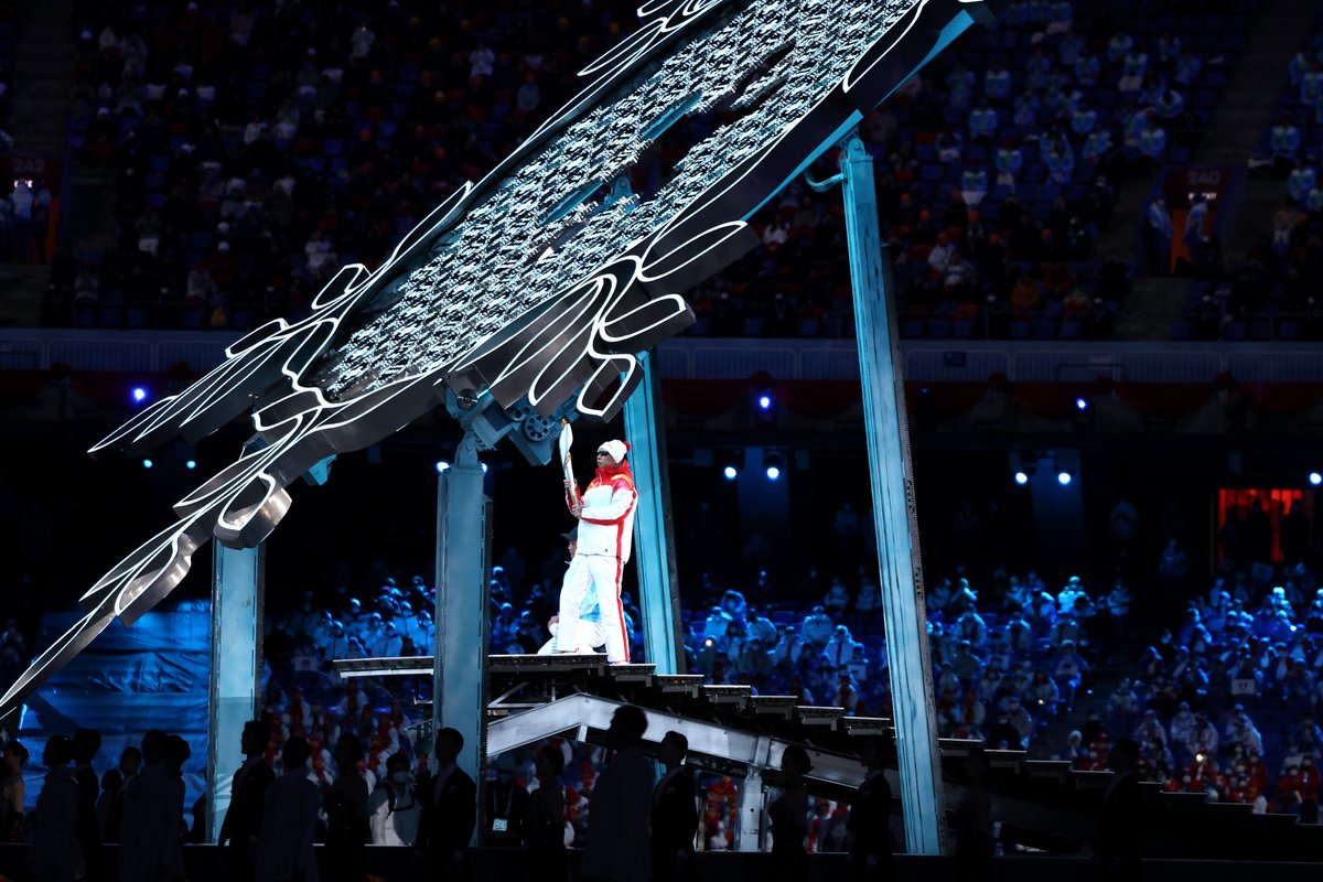Li Duan approaches a giant snowflake with the torch