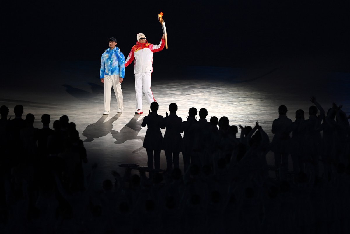 Li Duan is guided towards the cauldron as he holds up the torch