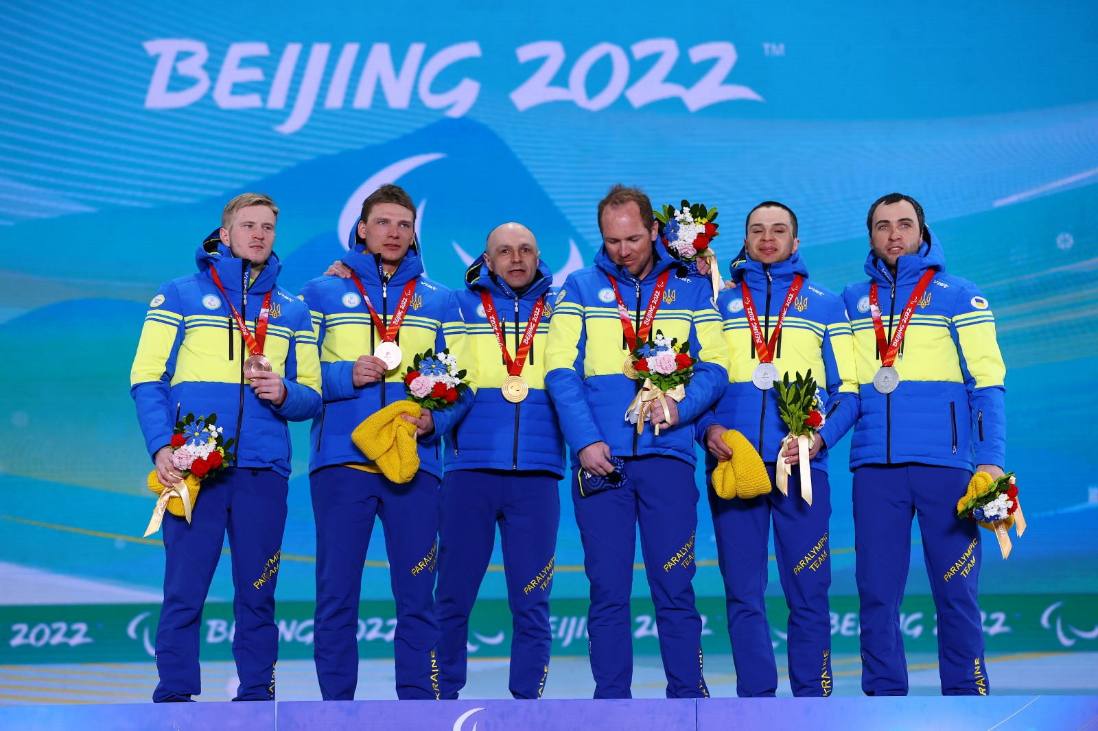 Ukraine team hold up their full set of biathlon medals on the podium 
