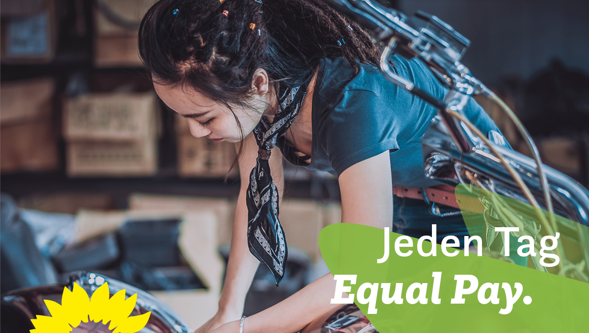 Auf dem Bild ist eine KfZ-Mechanikerin zu sehen, die an einem Motorrad hantiert. In der rechten unteren Ecke steht der Slogan: Jeden Tag Equal Pay.
