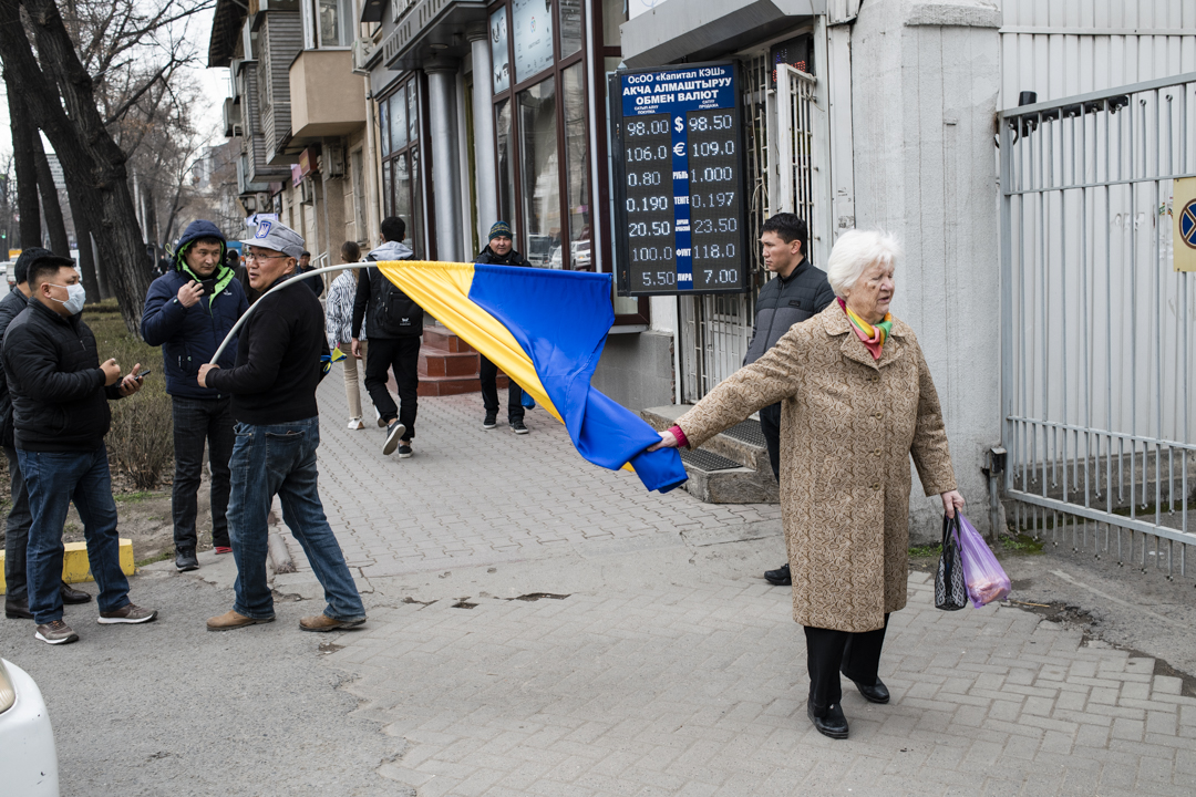 Peter__Leonard's tweet photo. A woman tries to grab a Ukrainian flag away from an anti-war protestor in front of the Russian Embassy in Bishkek, Kyrgyzstan, against the backdrop of a currency exchange outlet vividly illustrating the economic pressures of the war (Photo: Danil Usmanov) https://t.co/zgnh0JROhb