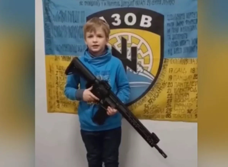 almayadeen_es's tweet photo. Un niño con un fusil posa frente a un símbolo nazi en un video propagandístico ucraniano https://t.co/YWPEmPHY0d #UNICEF #Fusil #NeoNazi #NaziUkraine #Ucrania #Rusia #Propaganda #DDHH https://t.co/HK0sG9ds44