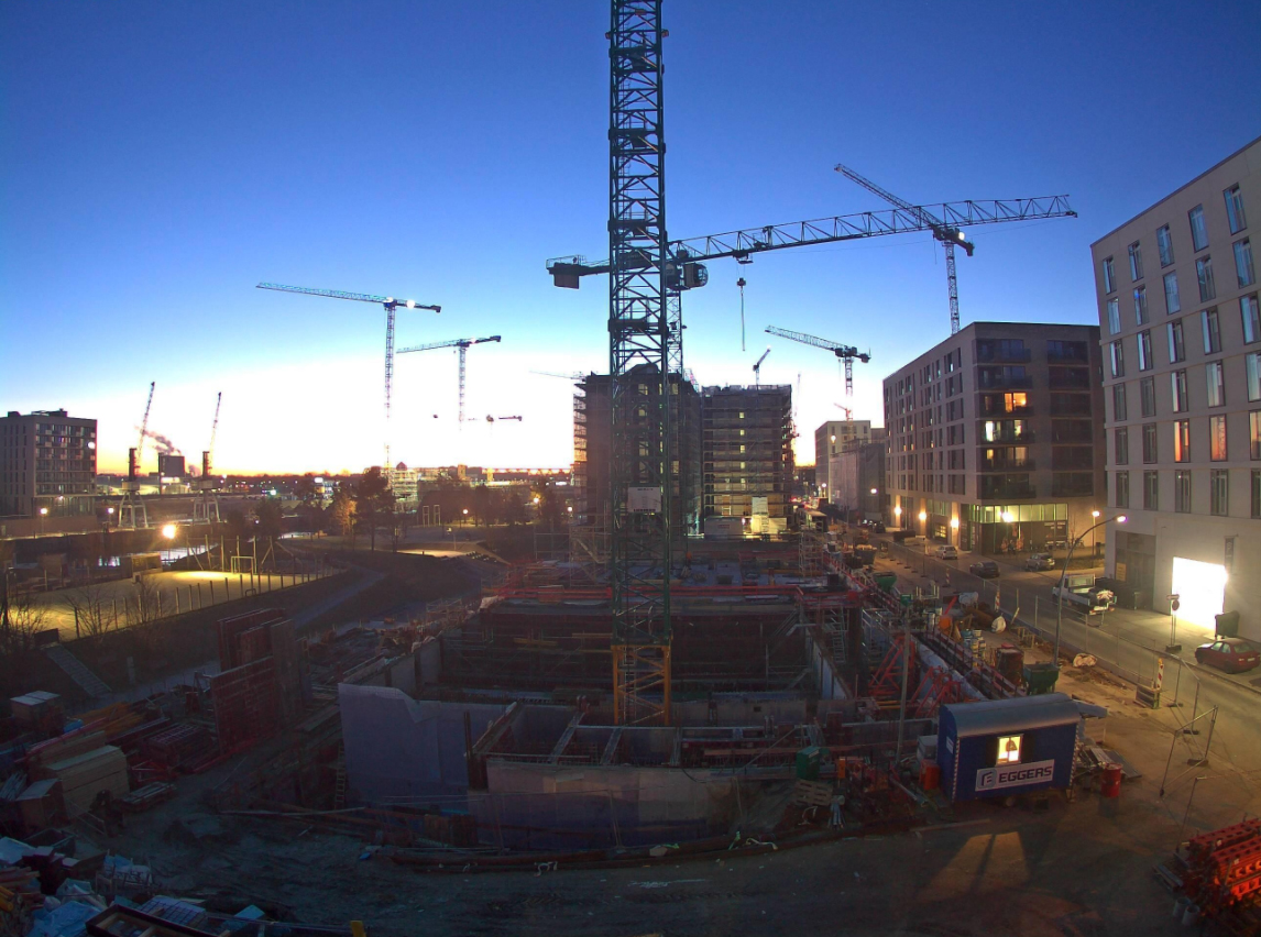 Baustelle der Schule Baakenhafen in der HafenCity. Im Vordergrund der Rohbau, Kräne der verschiedenen Baustellen. Im Hintergrund geht die Sonne auf.