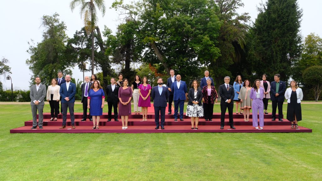 Presidente electo Gabriel Boric junto a las ministras y ministros de su gabinete. El Presidente está al centro de la imagen vestido con un terno azul marino y una camisa celeste.