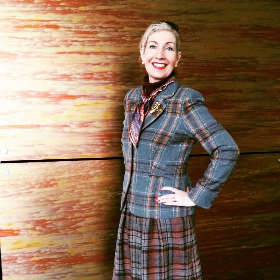 I'm standing against a bronze background wearing secondhand tweed