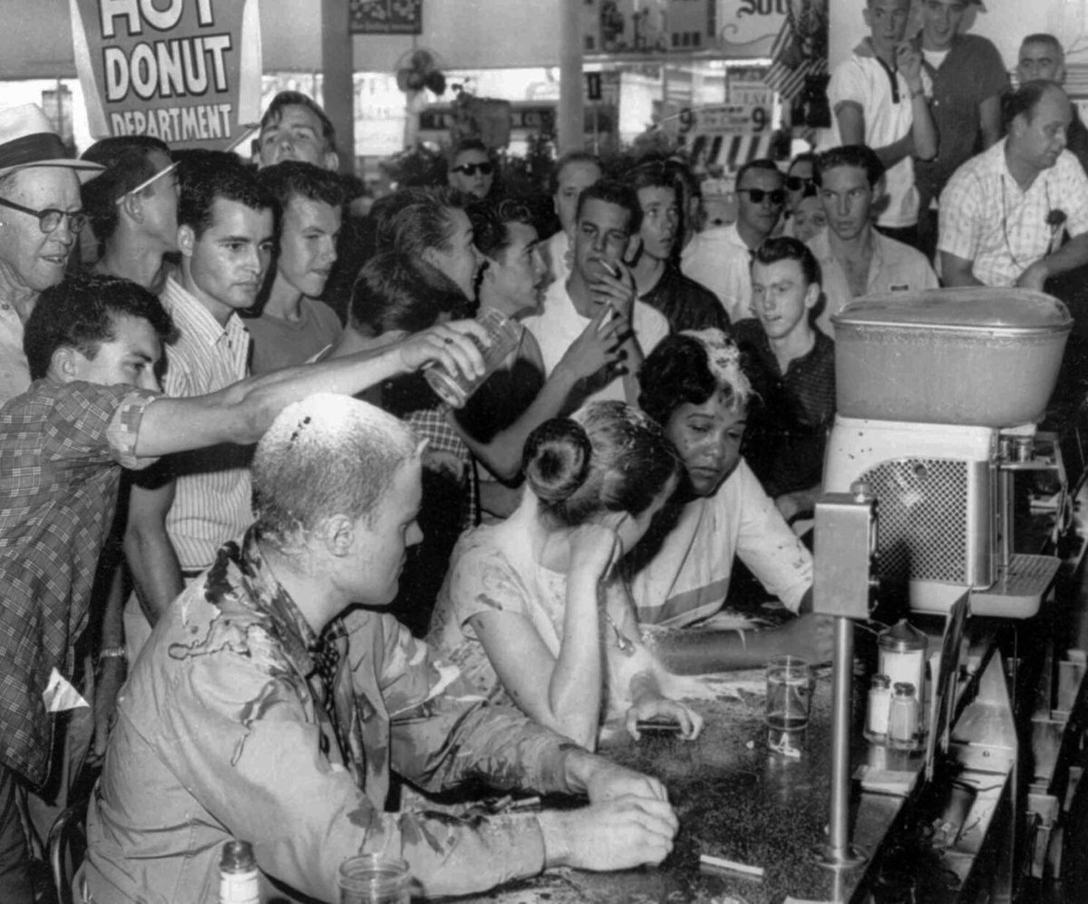 Una muchedumbre vierte azucar, ketchup y mostaza sobre las cabezas de John Salter, Joan Trumpauer y Anne Moody, sentados en la barra de una cafetería en protesta por su menú "solo para blancos".

Jackson, Mississippi, 28 de mayo de 1963 | 📸 Fred Blackwell