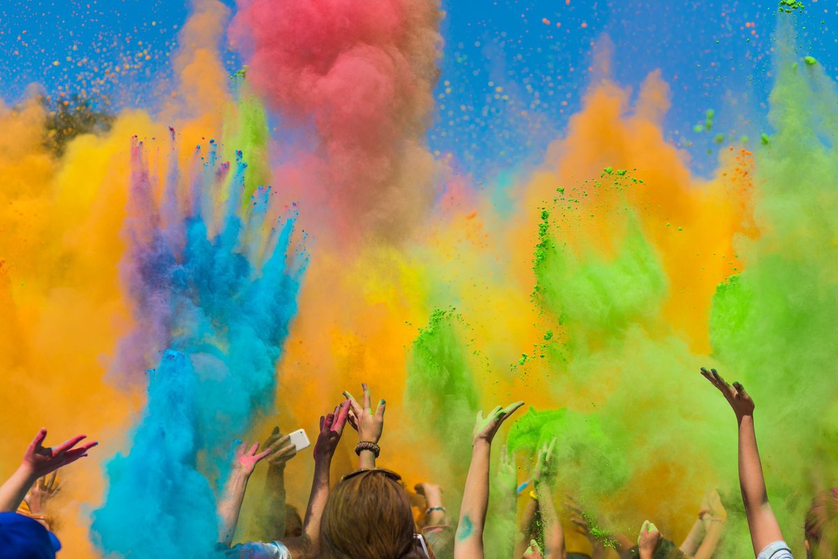 Hands throwing colorful powder into the air.