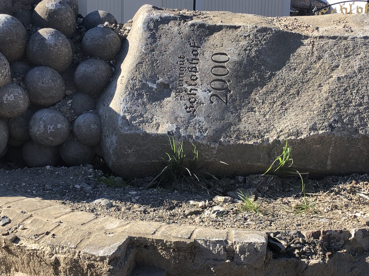 Basaltklotz, darauf Weintrauben (aus Stein?), Aufschrift Weingut Schlosshof 2000, auf der Seite liegend.