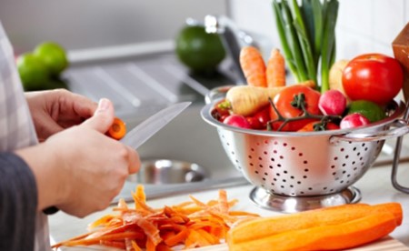 woman cleaning and cutting a variety of fresh vegetables 
