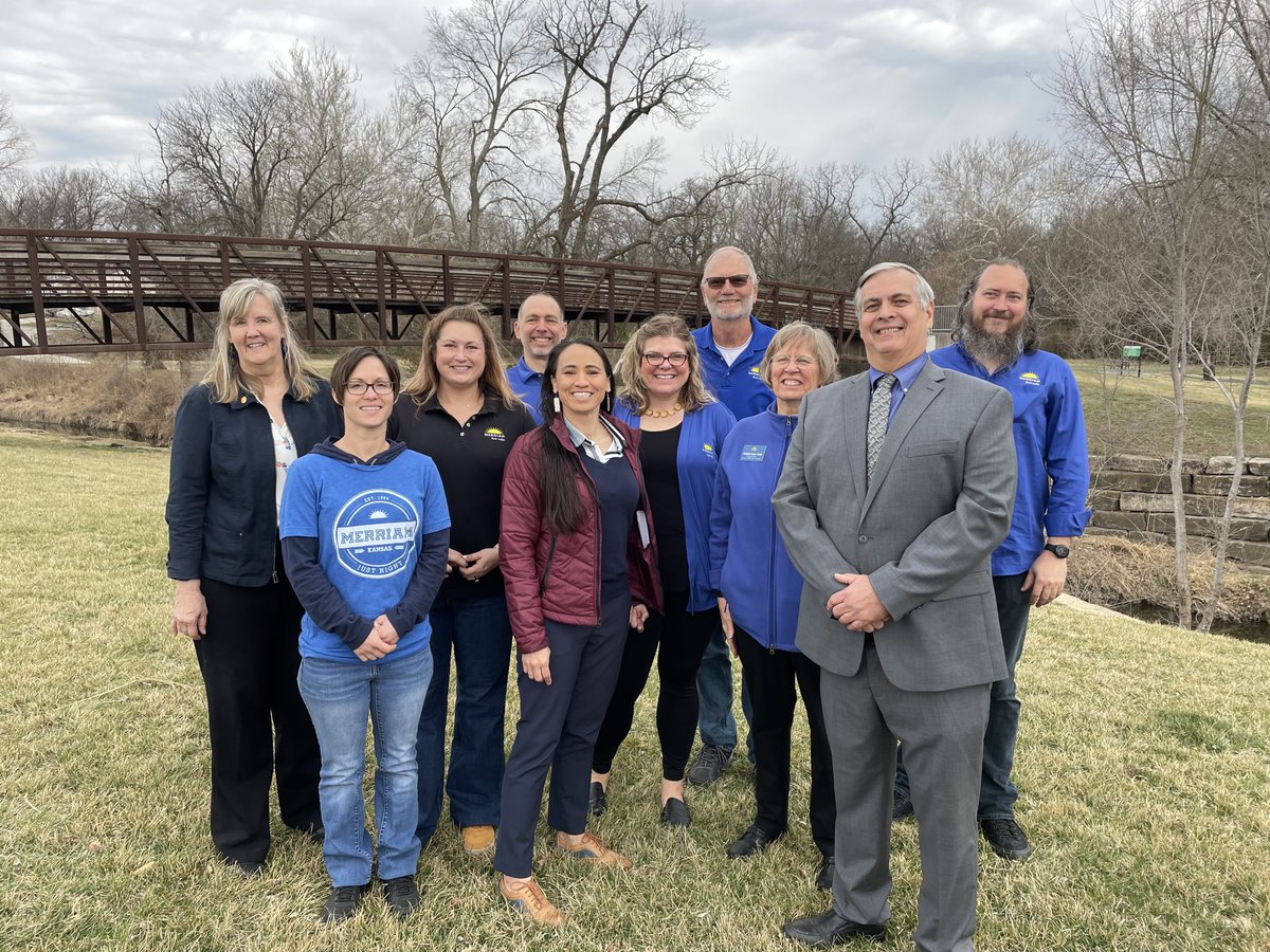 Group picture of Representative Sharice Davids, Merriam Mayor Bob Pape and local officials standing in front of Turkey Creek. 