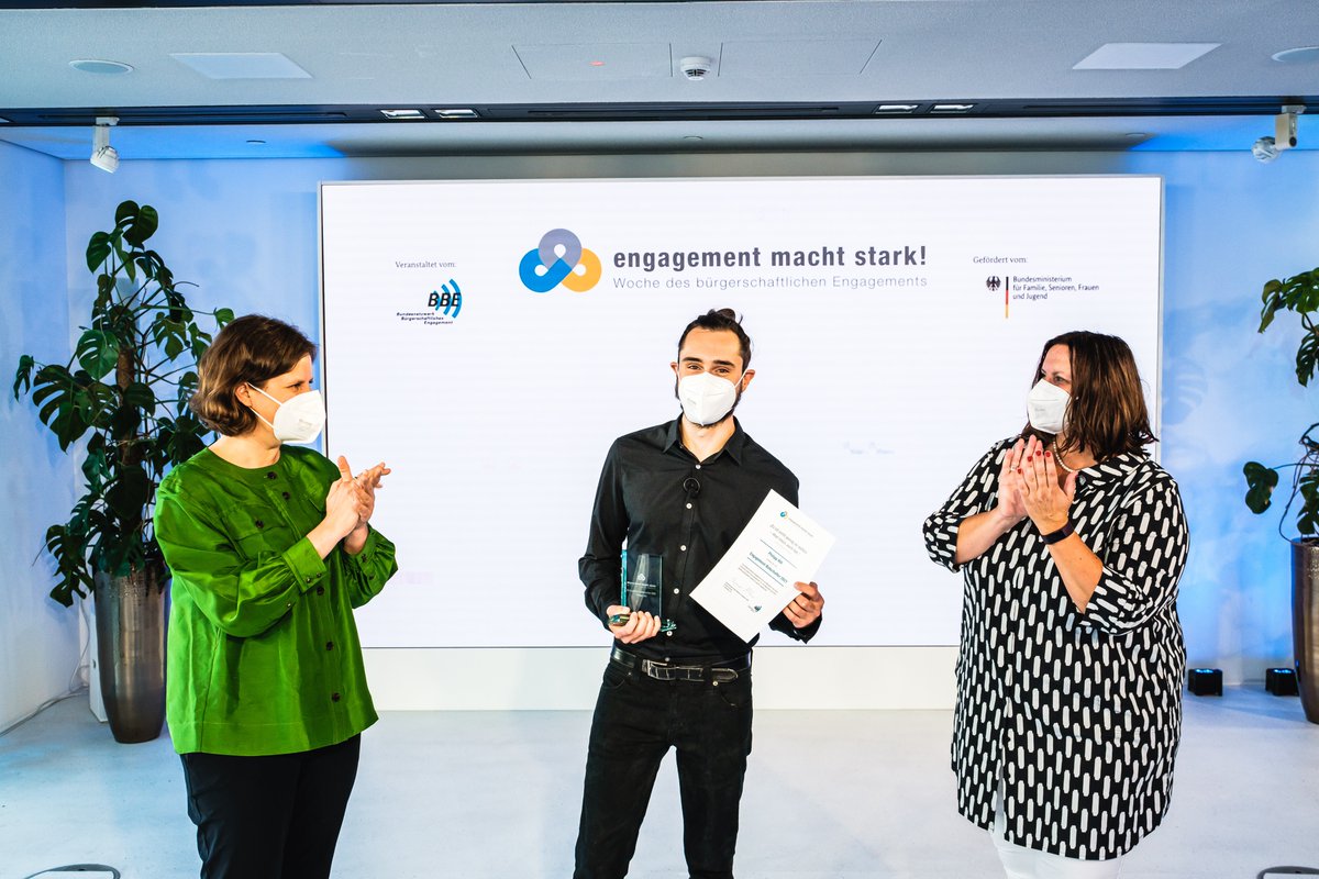 Drei Personen vor einer Leinwand mit der Aufschrift "Engagement macht stark."